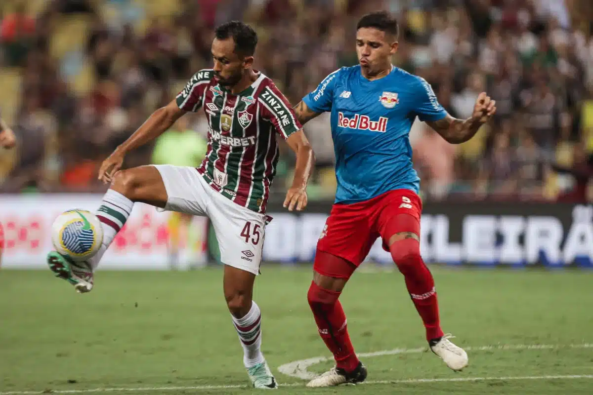 Jogador do Fluminense disputa a bola com jogador do Bragantino na intermediaria.
