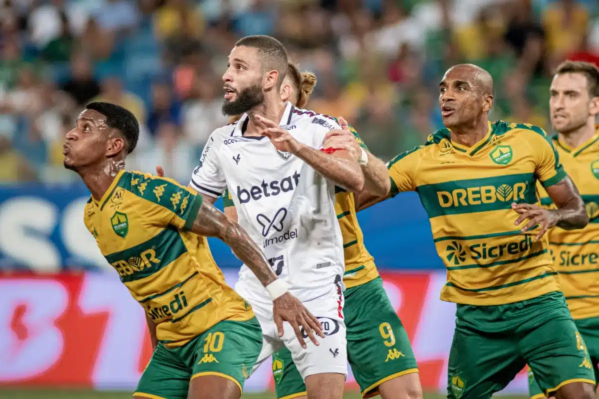 Jogadores do Cuiabá cercam jogador do Vitória em disputa pela bola em jogo pegado.