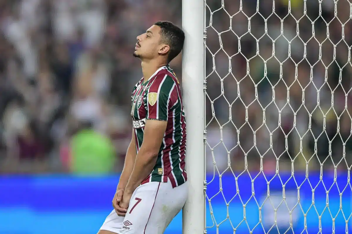 André, jogador do Fluminense, está recostado a uma trave e demonstra feição de tristeza.
