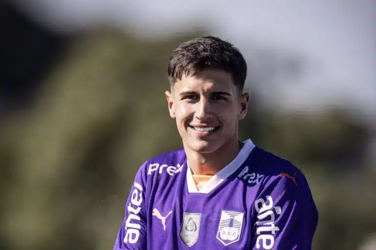Facundo Bernal sorri parra a câmera com uma camisa roxa do Defensor Sporting