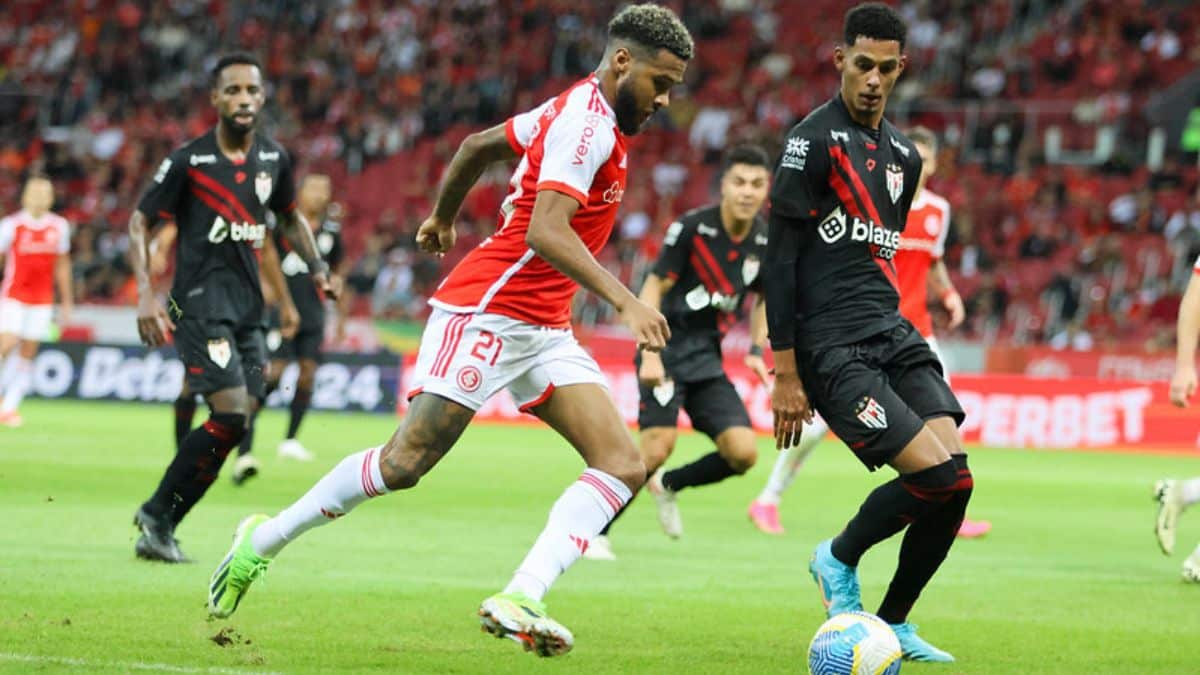 Jogador do Internacional conduz a bola sendo observado atentamente pelo jogador do Atlético-GO.