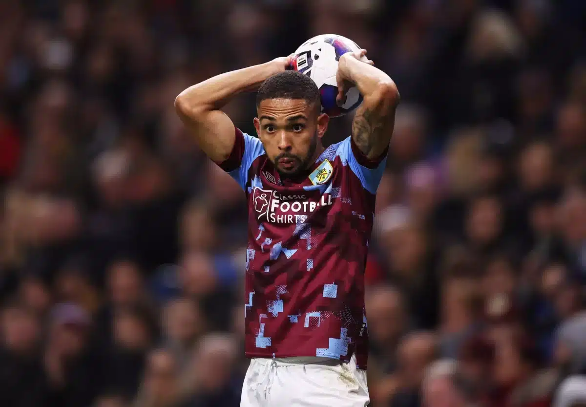 Vitinho, jogando pelo Burnley, está segurando a bola com as duas mãos e faz o movimento de arremessar bola em cobrança de lateral.