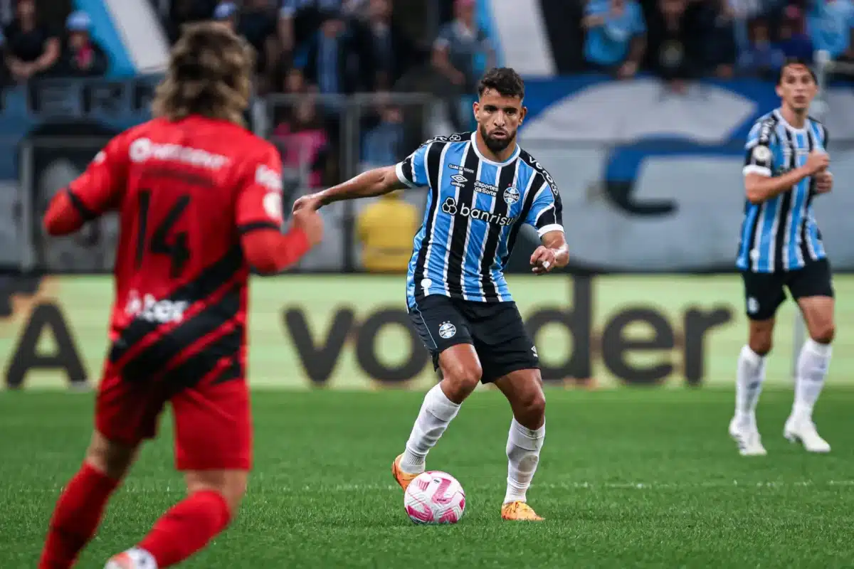 Jogador do Grêmio domina a bola enquanto jogador do Athletico-PR observa.