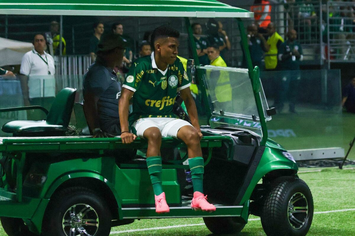 Estêvão, jovem revelação Palmeiras, está sentado no carro que serve de suporte para tirar jogadores lesionados do gramado do estádio Allianz Parque.