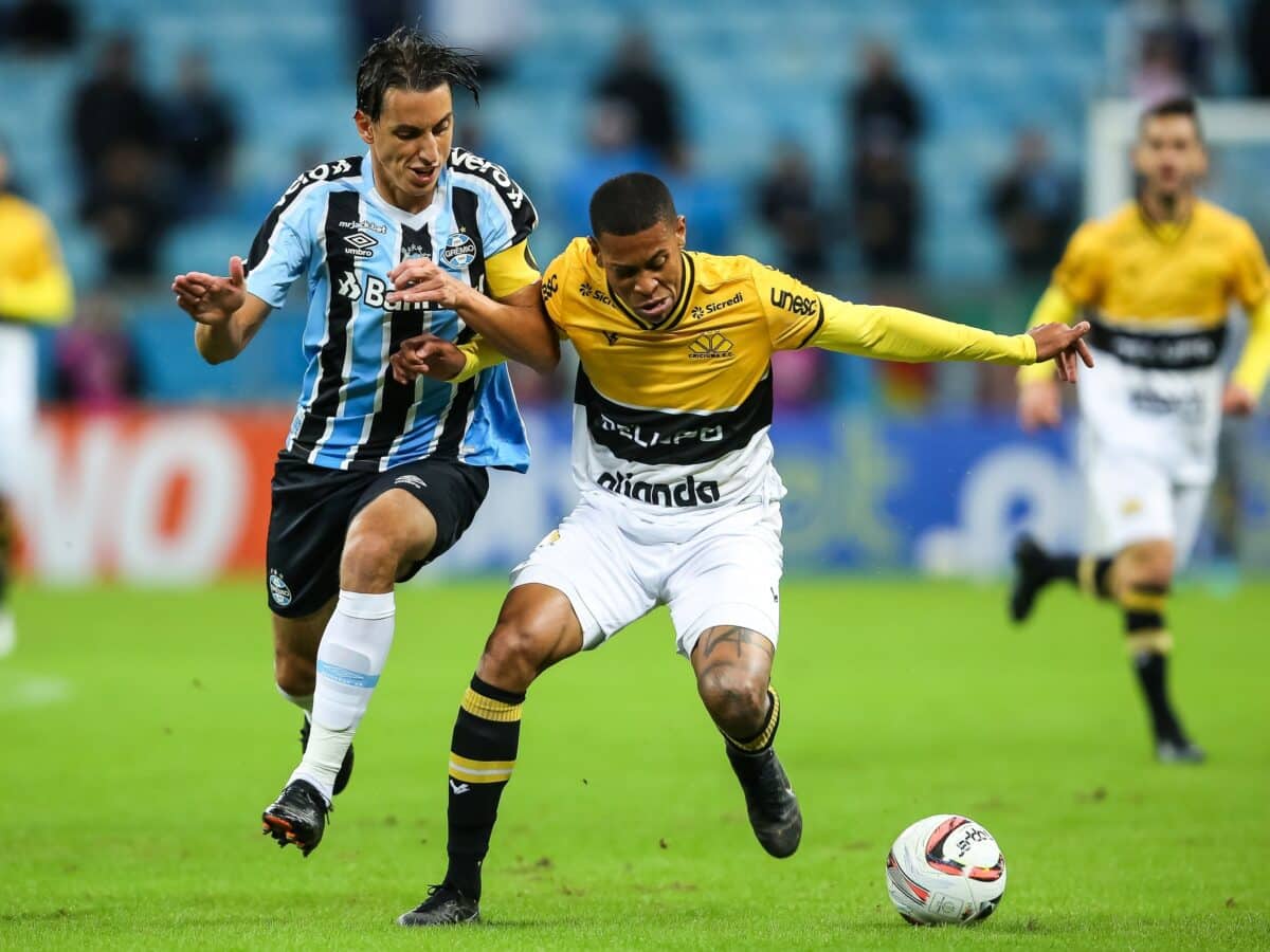 Jogador do Grêmio disputa lance com jogador do Criciúma.