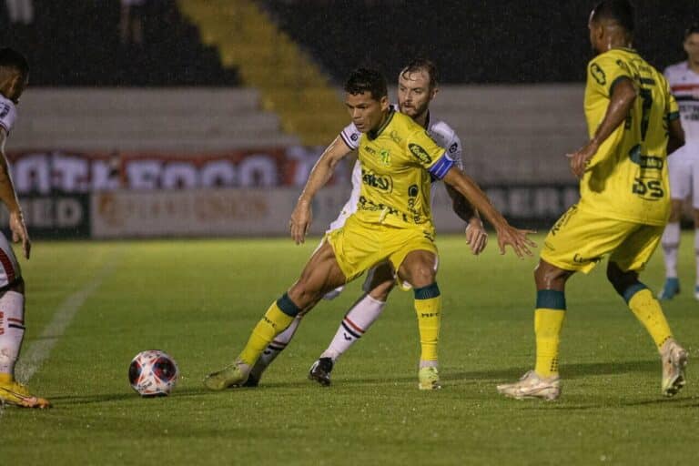 Jogadores do Mirassol e do Botafogo-SP disputando a bola na lateral do campo.