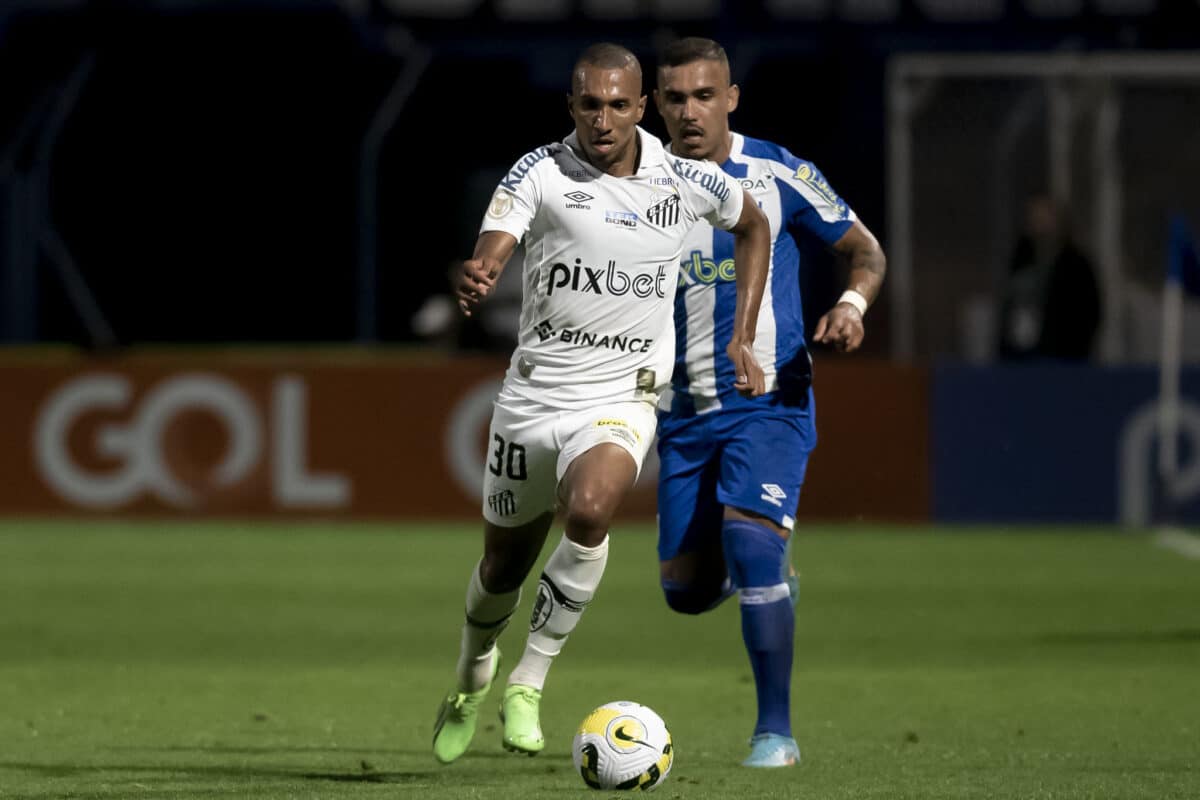 Jogador do Santos corre com s bola dominada e é perseguido por jogador do Avaí.