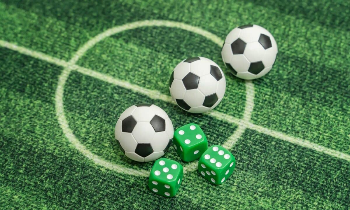 Gramado de futebol com 3 bolas de futebol nas cores preto e branco, e 3 dados verdes