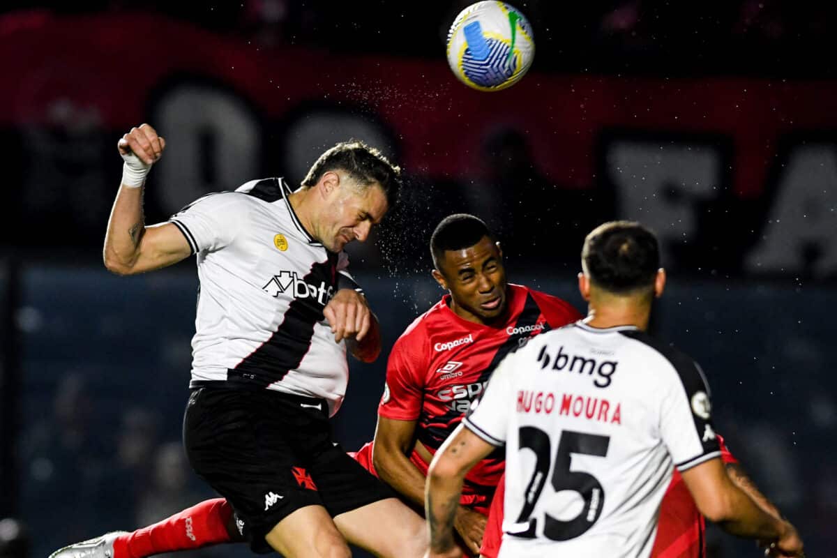 Jogador do Vasco disputa bola no alto com jogadores do Athletico-PR.