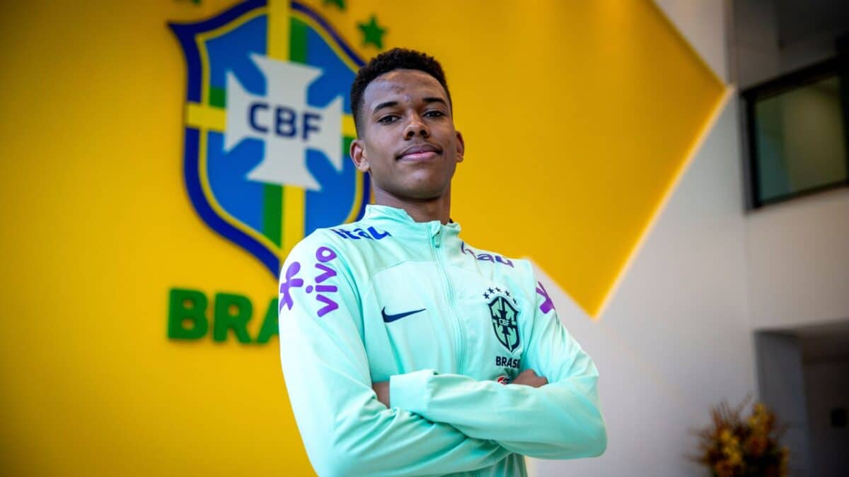 O jovem craque Estevão pousa com o agasalho de treino da seleção brasileira. Ao fundo, está o escudo da CBF.