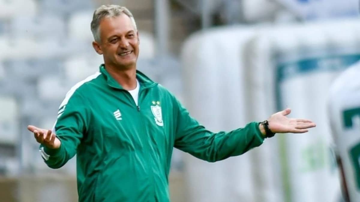 O técnico Lisca, com o blusão de treino da América-MG, é fotografado rindo e com os braços abertos.