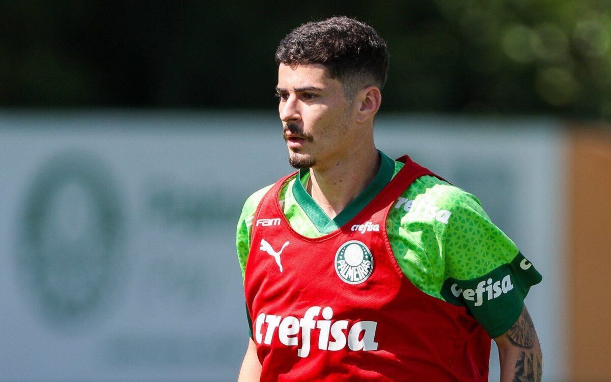 Rômulo, jogador do Palmeiras, está vestido com colete vermelho de treino do clube paulista.